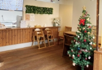 川口市の「CHURROS SHOP 1008 SENYA」の店内。木目調のカウンターと床、テーブル席があり、クリスマスツリーが飾られている。