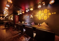 「スパイス研究所 MAD CHEFs 蒲田店」の内観。ダークトーンの壁にゴールドの装飾が施され、天井からは色とりどりのトルコランプ風の照明が吊るされている。ゆったりとしたソファ席が並ぶ落ち着いた空間。